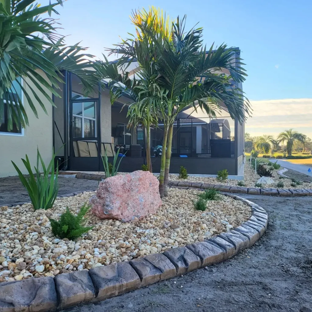 Curved concrete landscape curbing with rock bed and tropical plants